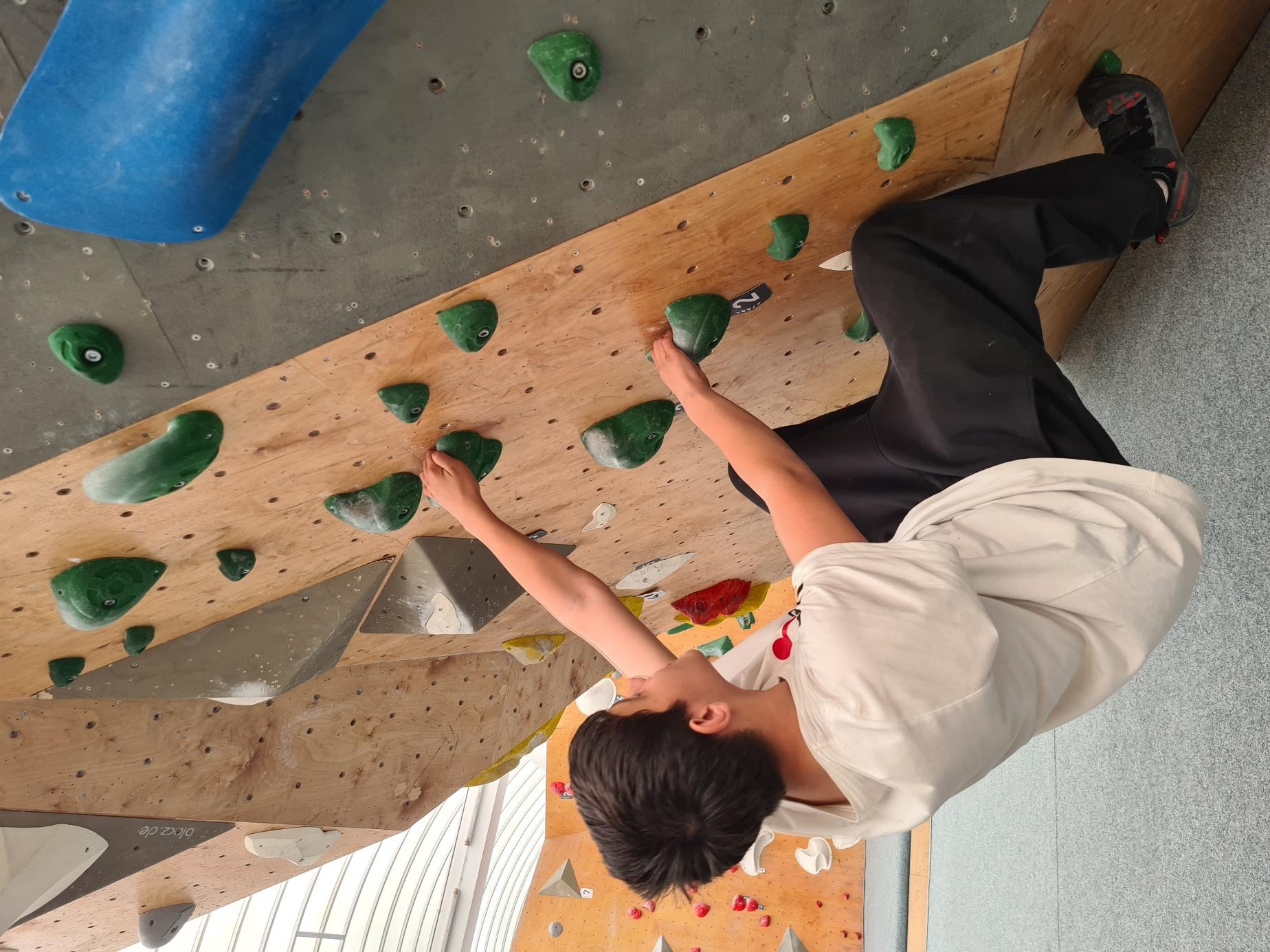 Ein Schüler klettert an der Boulderwand